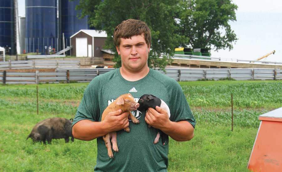 Noah Taylor holding two piglets