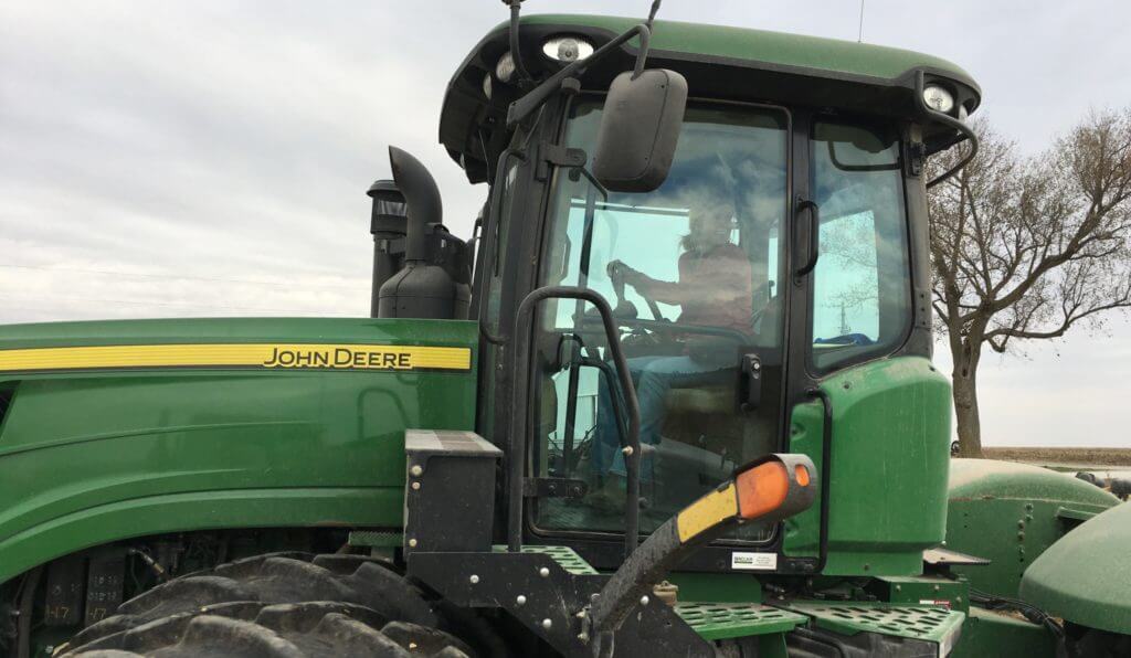 Hannah Taylor driving a green john deere tractor