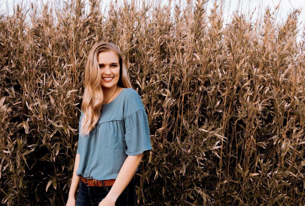 Ruthie Carpenter standing in front of plant stalks